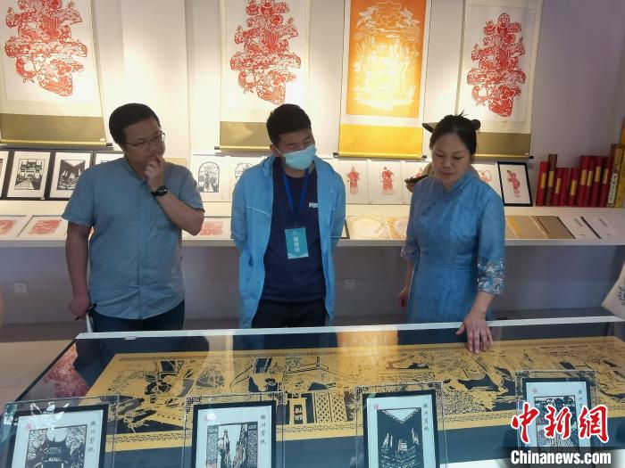 安徽省非遗徽州剪纸传承人吴笑梅(右一)在介绍自己的作品。 张强 摄 安徽省非遗徽州剪纸传承人吴笑梅(右一)在介绍自己的作品。 张强 摄